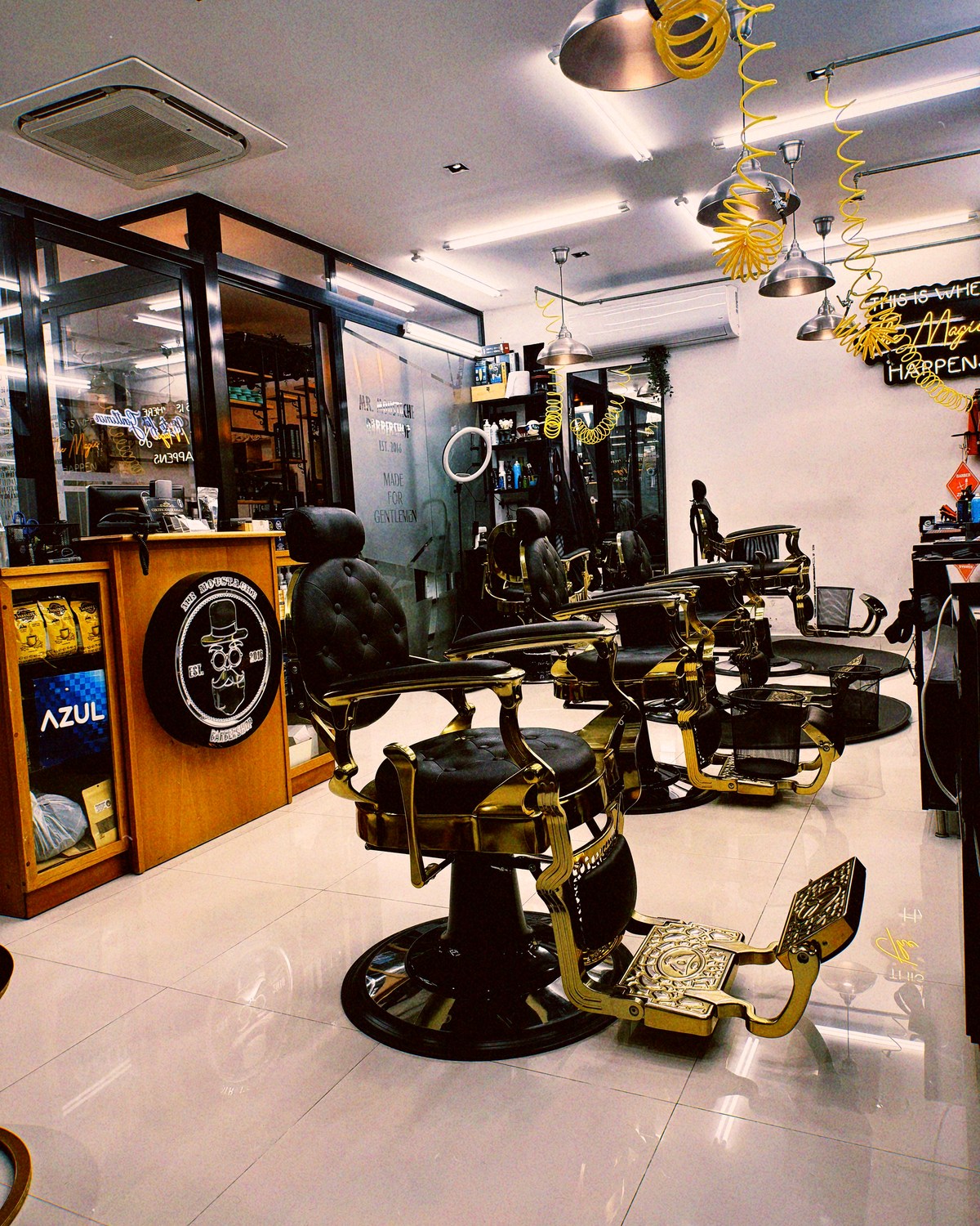 Mr. Moustache Barbershop — el salón completo con la fila de sillones dorados, la recepción y el letrero de neón